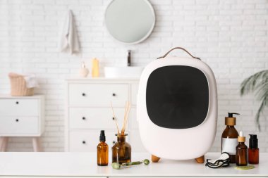 Temel yağ ve yayıcılı küçük kozmetik buzdolabı beyaz arka planda. Yakın çekim.