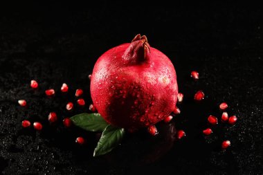 Lezzetli olgun nar ve siyah arka planda tohumlar, yakın plan.