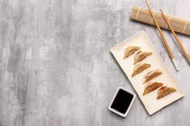 Kızarmış Japon gyoza tabağı ve gri arka planda soya sosu.