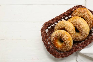 Beyaz ahşap arka planda susam tohumlu bir sepet lezzetli simit.