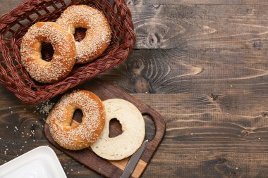 Tahta ve hasır sepet dolusu tahtadan arkaplanda susam tohumları olan lezzetli simit.