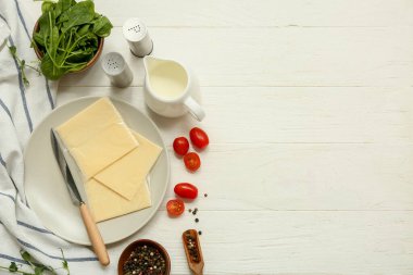 Lezzetli işlenmiş peynir dilimleri ve beyaz ahşap masada taze sebzelerle dolu bir tabak.