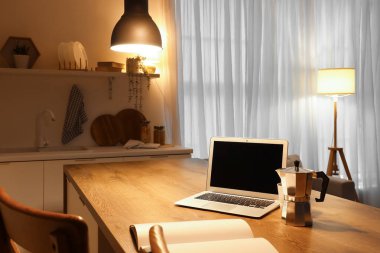 Geceleri mutfakta kahve makinesi olan boş bir dizüstü bilgisayar.