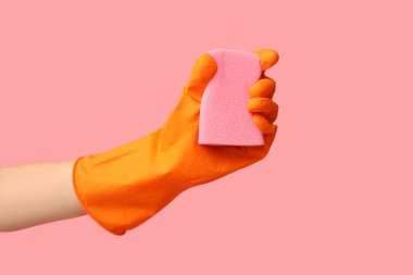 Pembe arka planda süngeri olan bir kadın eli. Küf temizleme kavramı