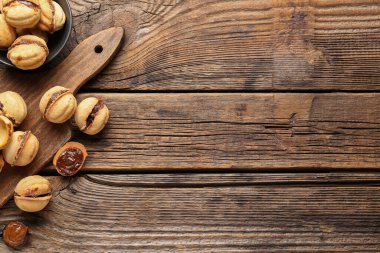 Tahta zemin üzerinde kaynamış konsantre süt ve ceviz şeklinde kurabiyeler kâse ve kesme tahtası.