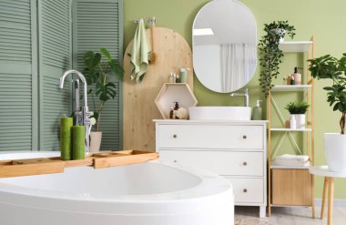 Banyonun içinde küvet, lavabo ve yeşil katlama ekran var.