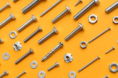 Turuncu arka planda farklı musluk cıvataları, vidalar ve krom fındıklar düzenleme