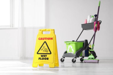 Uyarı levhası ve tramvayla aydınlık odada temizlik malzemeleri.