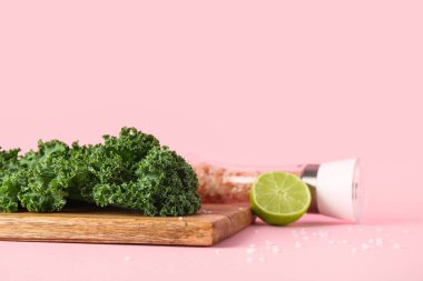 Ahşap tahta tahta üzerinde taze lahana yaprakları ve pembe arka planda limon.