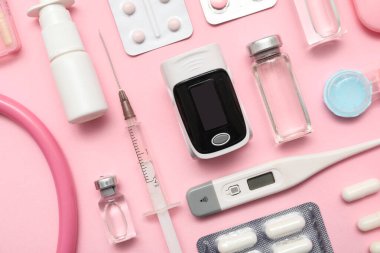 Pembe arka planda nabız oksimetresi, termometre ve ilaç bileşimi, yakın plan.