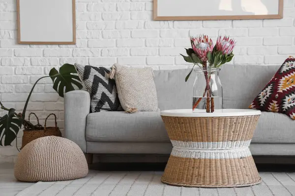 Oturma odasındaki masada protea çiçekleri olan vazo.