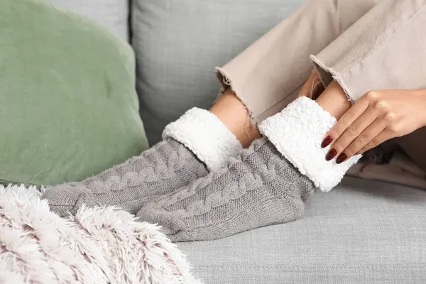Sıcak çoraplı bir kadın evdeki kanepede oturuyor.
