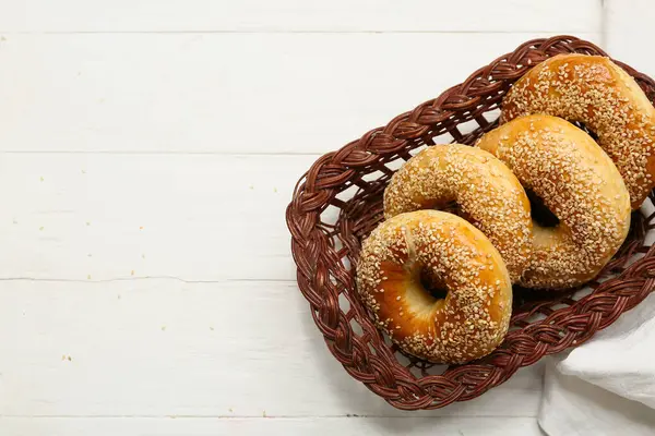 Beyaz ahşap arka planda susam tohumlu bir sepet lezzetli simit.