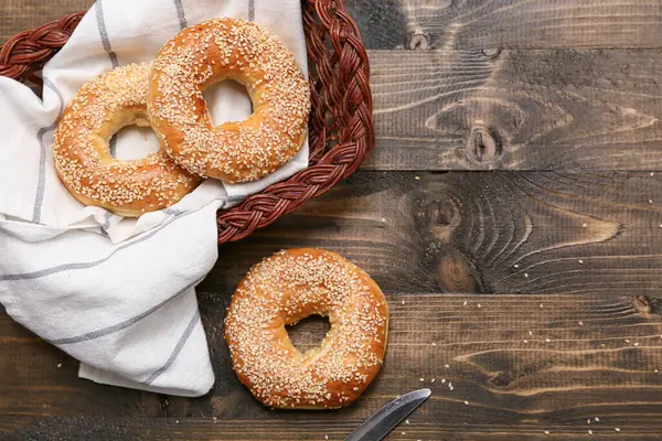 Tahta arka planda susam tohumlu bir sepet lezzetli simit.