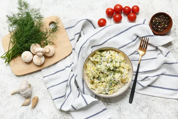 Bir kase lezzetli patates salatası, malzemeli ve çatallı hafif grunge arka plan.