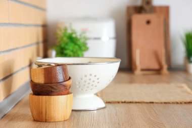 Kolander ve ahşap kaseler mutfaktaki masada, yakın plan.