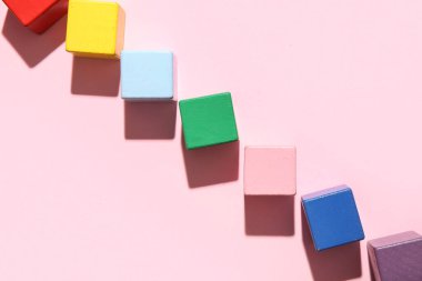 Pembe arka planda farklı renkli yapı küpleri