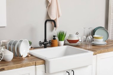 Şık seramik lavabo ve ahşap mutfak tezgahında temiz tabaklar.