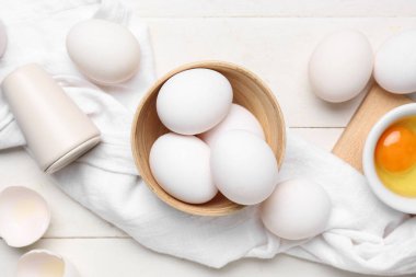 Beyaz ahşap arka planda çiğ tavuk yumurtası ile kase