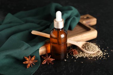 Ahşap tahta tahta, gerekli yağ, kaşık, anason yıldızları ve siyah grunge arka planda kurumuş tohumlar.