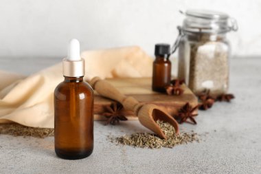 İçinde gerekli yağ şişeleri, anason yıldızları, kurutulmuş tohumlar ve gri grunge masasında kepçe bulunan ahşap tahta tahta.