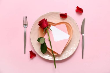 Zarflı güzel bir masa ve pembe arka planda kırmızı gül. Sevgililer Günü kutlaması