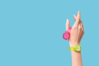 Mavi arka planda kol saatleri olan bir kadın el.