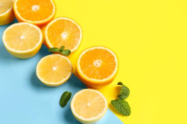 Renk arkaplanında nane yapraklarıyla portakal ve limon kes