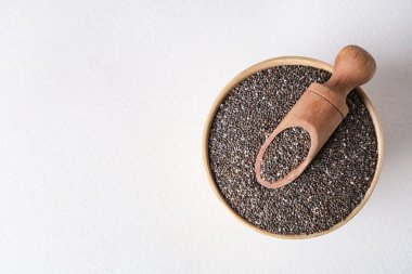 Beyaz zemin üzerinde chia tohumları olan kase ve ahşap kepçe