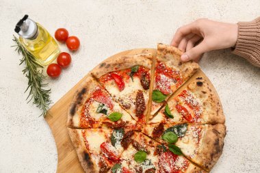Kadın eli arka planda lezzetli bir pizzayı alıyor.