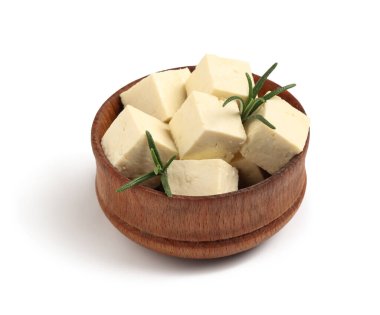 Beyaz arka planda kesilmiş tofu peyniri ve biberiye dallarıyla dolu bir kase.