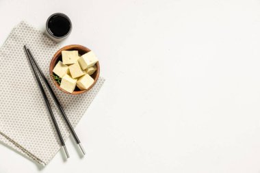 Beyaz arka planda lezzetli tofu peyniri parçaları olan bir kase.