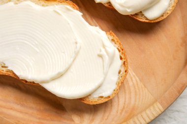 Gri arka planda işlenmiş peynirli ahşap bir tabak lezzetli bruschetta. Yakın çekim.