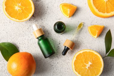 Portakal yağı şişeleri ve beyaz arka planda taze meyveler.