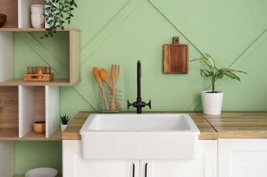 Lavabosu, beyaz tezgahları ve rafları olan şık bir mutfak.