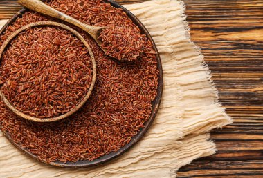 Tabak, tabak ve kaşık, ahşap zemin üzerinde çiğ kahverengi pirinç.