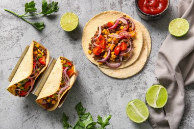 Gri arka planda lezzetli tacolar ve malzemeler.