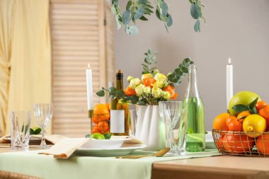 Oturma odasında narenciye, içki şişeleri ve çiçeklerle dolu bir masa. Yakın çekim.