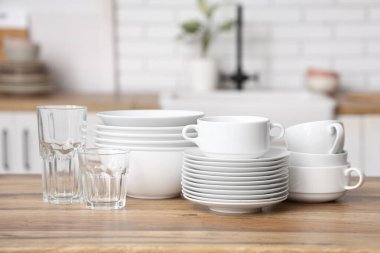 Mutfaktaki ahşap masada yığınla tabak ve bardak.