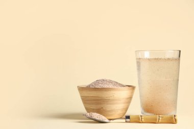 Bej arka planda psyllium kabuğu olan bir bardak su.