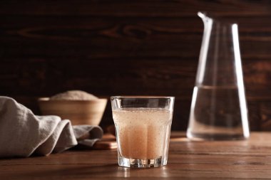 Tahta zemin üzerinde psyllium kabuğu olan bir bardak su.