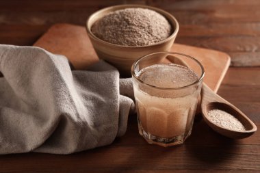 Tahta zemin üzerinde psyllium kabuğu olan bir bardak su.