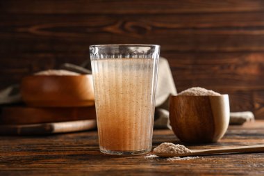 Tahta zemin üzerinde psyllium kabuğu olan bir bardak su.