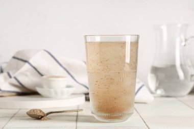 Hafif zemin üzerinde psyllium kabuğu olan bir bardak su.