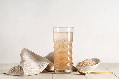 Hafif zemin üzerinde psyllium kabuğu olan bir bardak su.