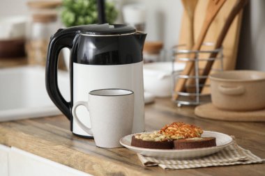 Modern elektrikli çaydanlık, mutfakta sıcak çay ve tatlı kekler.