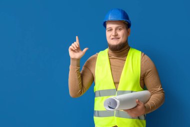 Mavi arka planda bir şeyler çizen genç erkek mühendis.