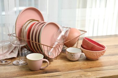 Mutfak penceresinin yanındaki tezgahta temiz pembe tabakları olan tutucu.