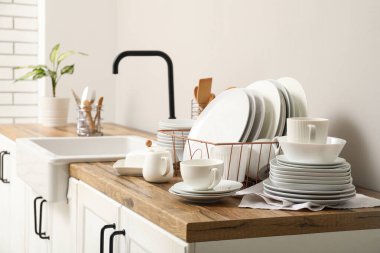 Mutfakta lavabonun yanında temiz beyaz tabakları olan bir tutucu.