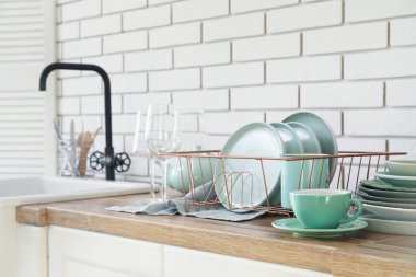 Mutfaktaki lavabonun yanında temiz yeşil tabakları olan tutucu.